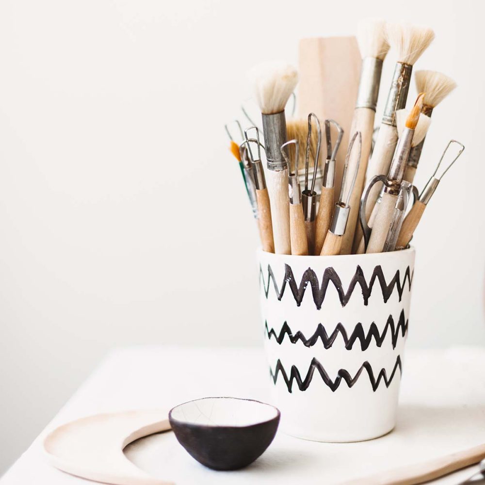 close-up-modern-handmade-mug-with-pottery-tools-at-WQX69JZ.jpg